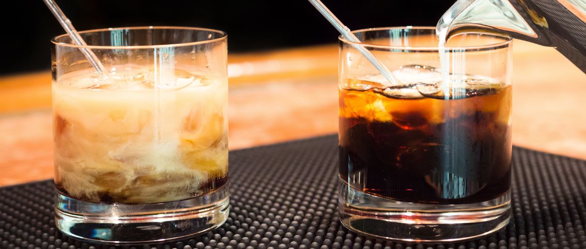 Two glasses of drinks along with straws at a place