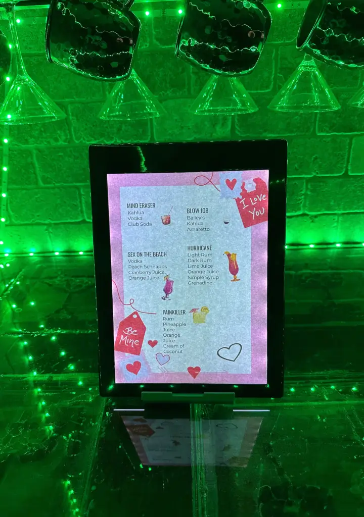 Illuminated cocktail menu with green background lighting.